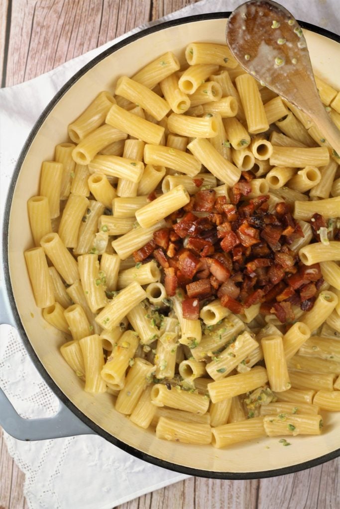 large skillet filled with pasta topped with cubed pancetta