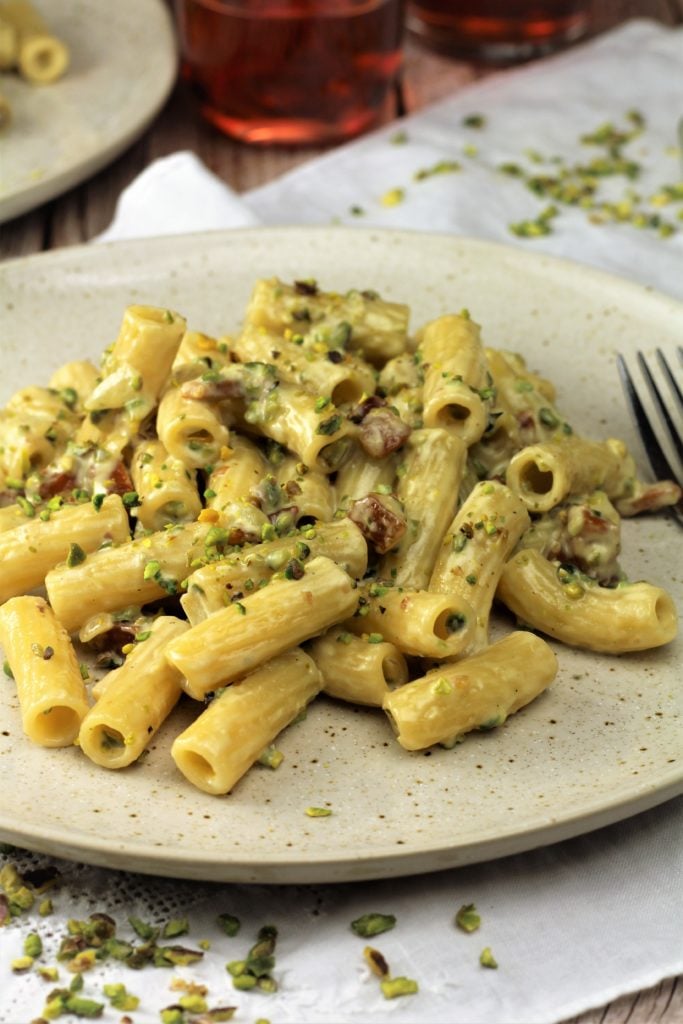 plate filled with creamy pistachio pasta topped with chopped pistachios