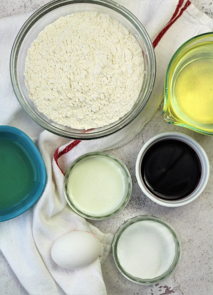 bowls with flour, wine, sugar, milk, oil and an egg