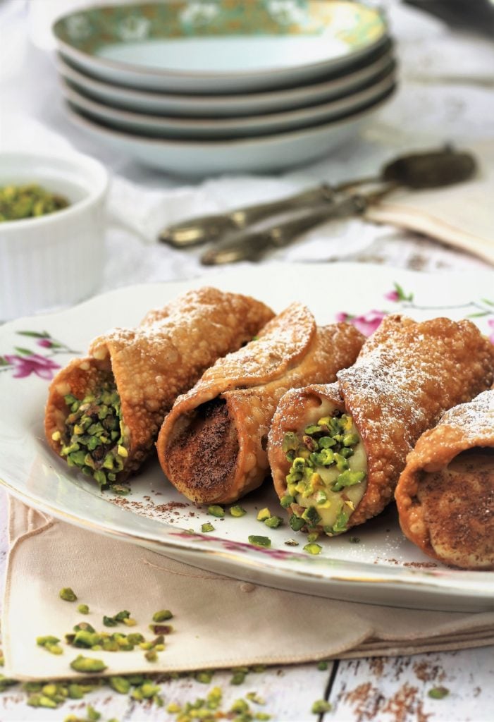 cannoli filled with pastry cream and topped with pistachios and grated chocolate