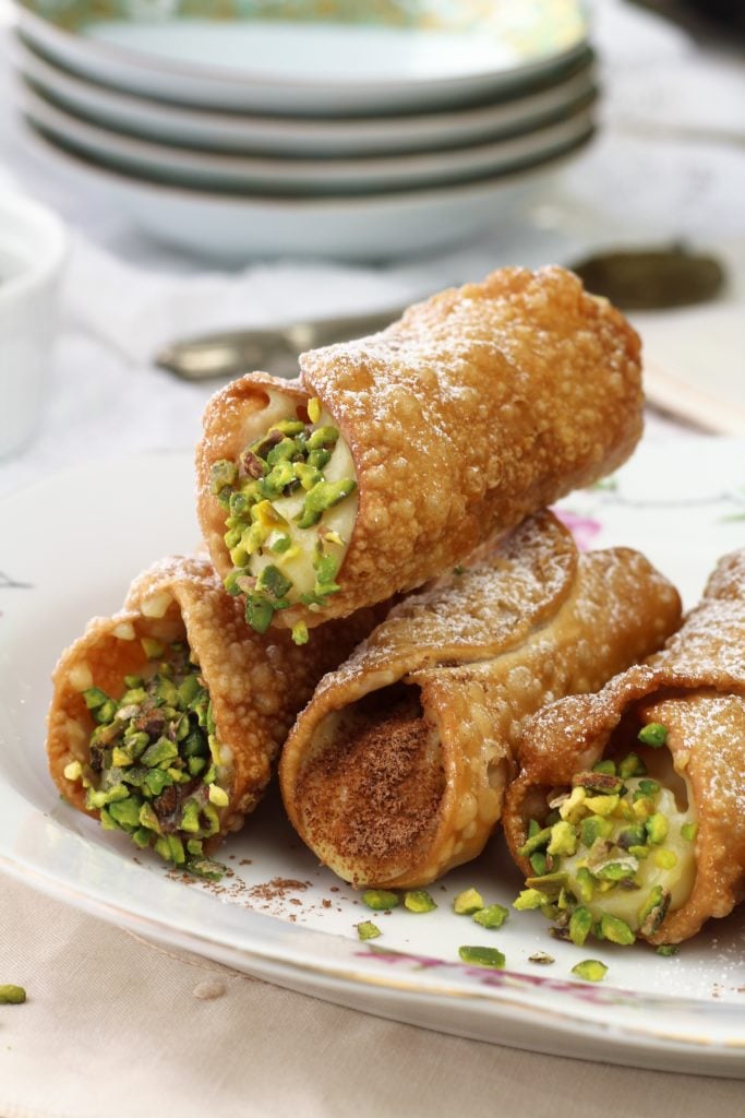 pistachio and grated chocolate topped Sicilian cannoli with pastry cream piled on plate