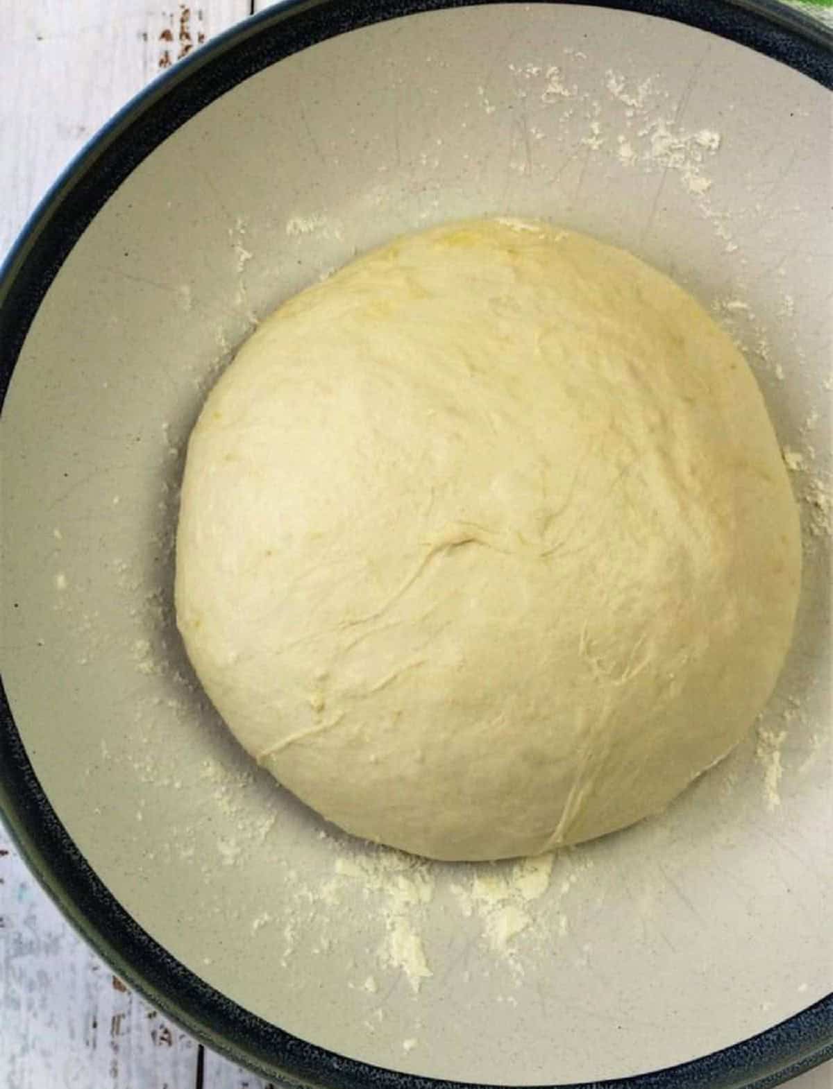 No knead pizza dough ball in bowl for pizza rolls.