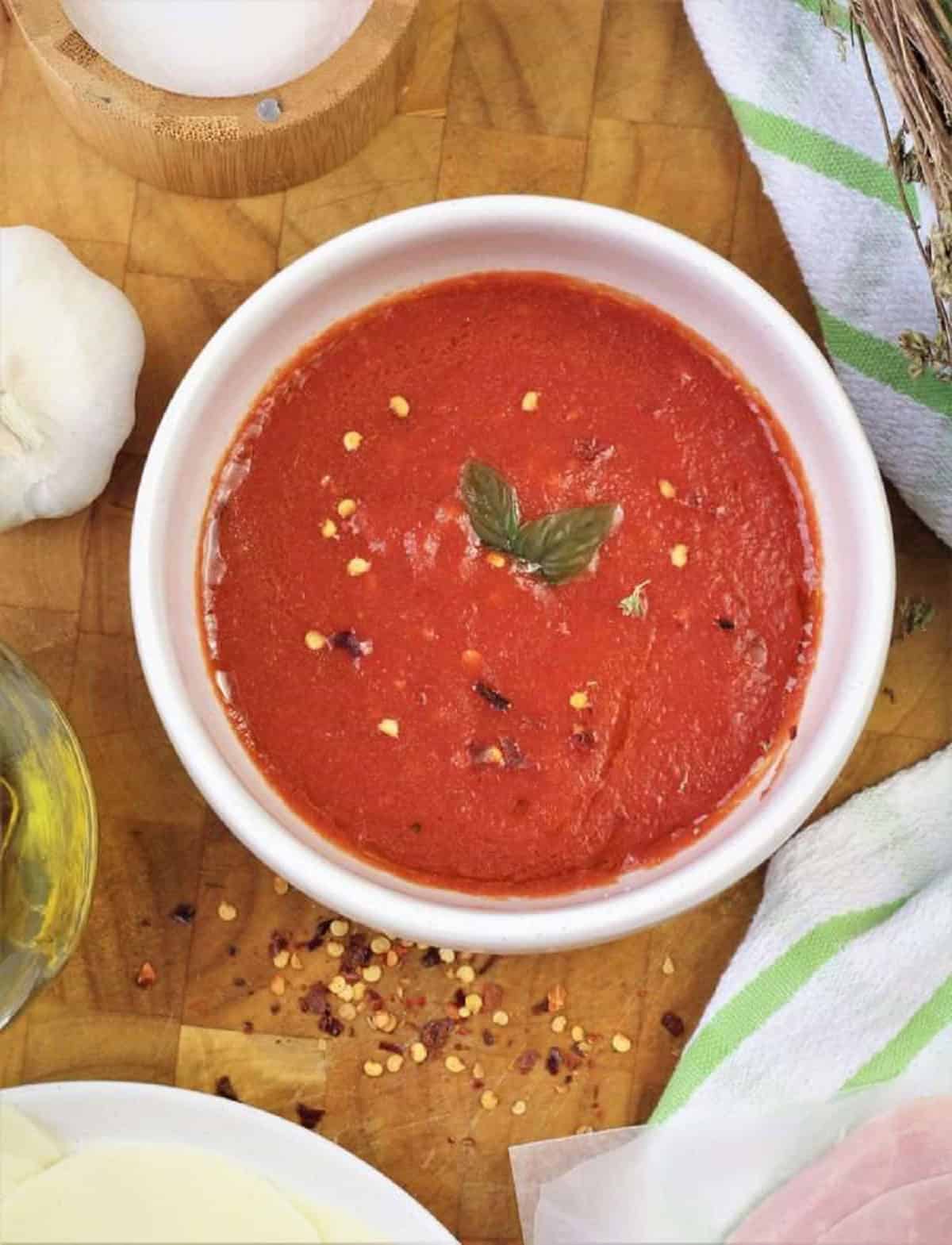 Easy no cook pizza sauce in bowl topped with fresh basil for pizza rolls.