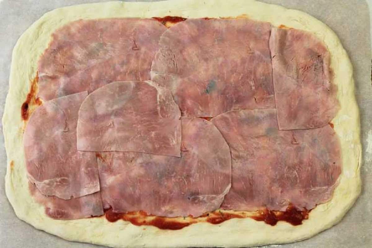 No knead pizza dough topped with prosciutto cotto slices.