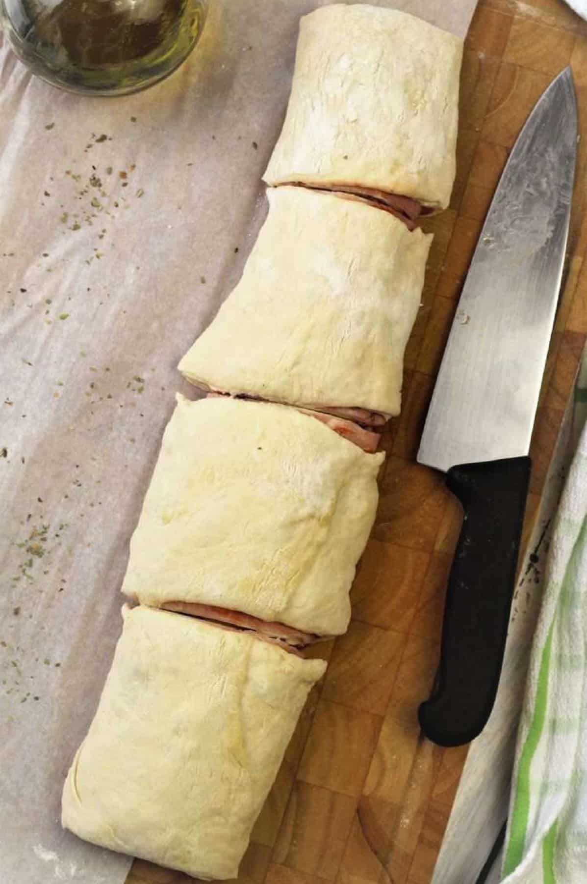 Rolled pizza dough cut into sections for pizza rolls.