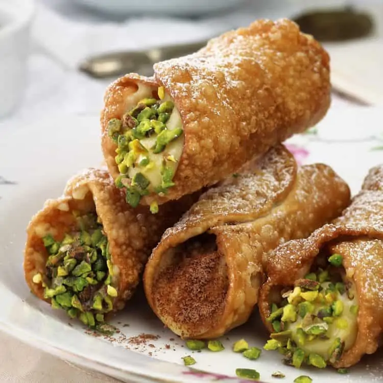 pistachio and chocolate topped pastry cream filled cannoli on plate
