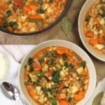 bowls filled with minestrone soup alongside pot filled with soup