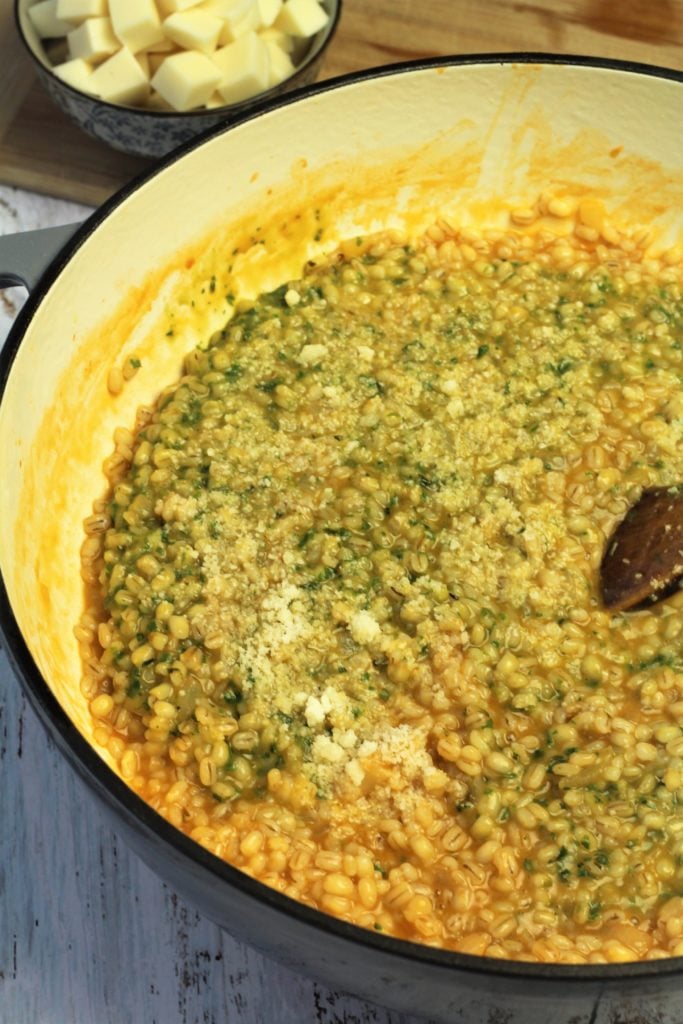 barley risotto in skillet with pesto and grated cheese stirred in