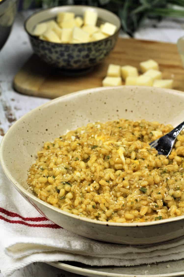 bowl of barley risotto with fork in it and bowl of mozzarella in background