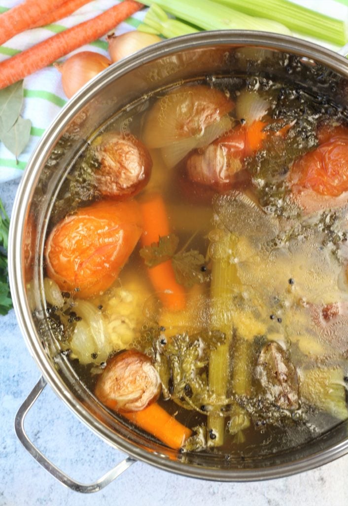 large stock pot with simmered chicken broth filled with vegetables 
