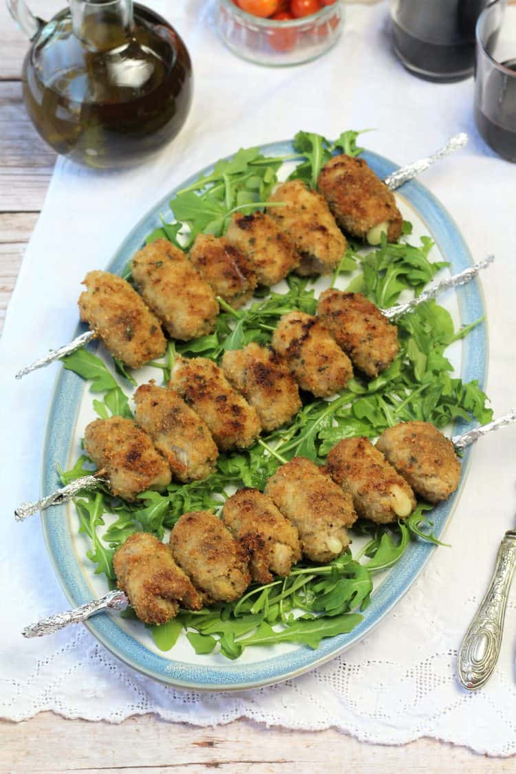plate of skewered veal involtini served over arugula