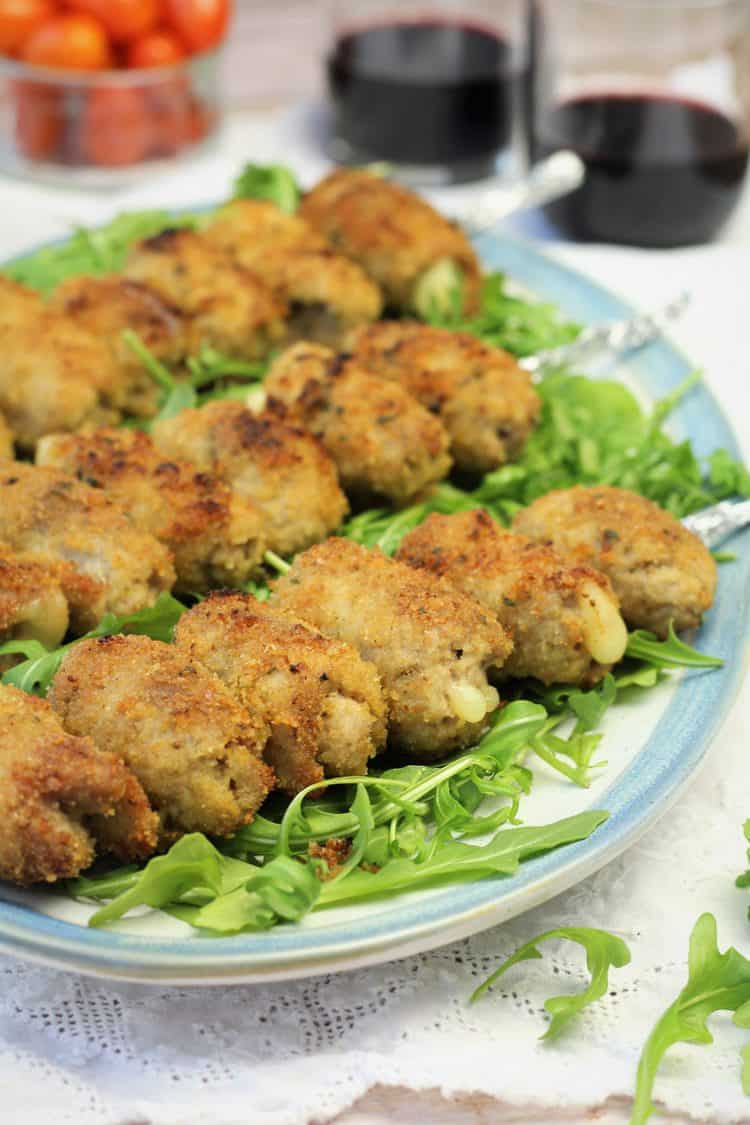 breaded veal rolls on a skewer served over arugula