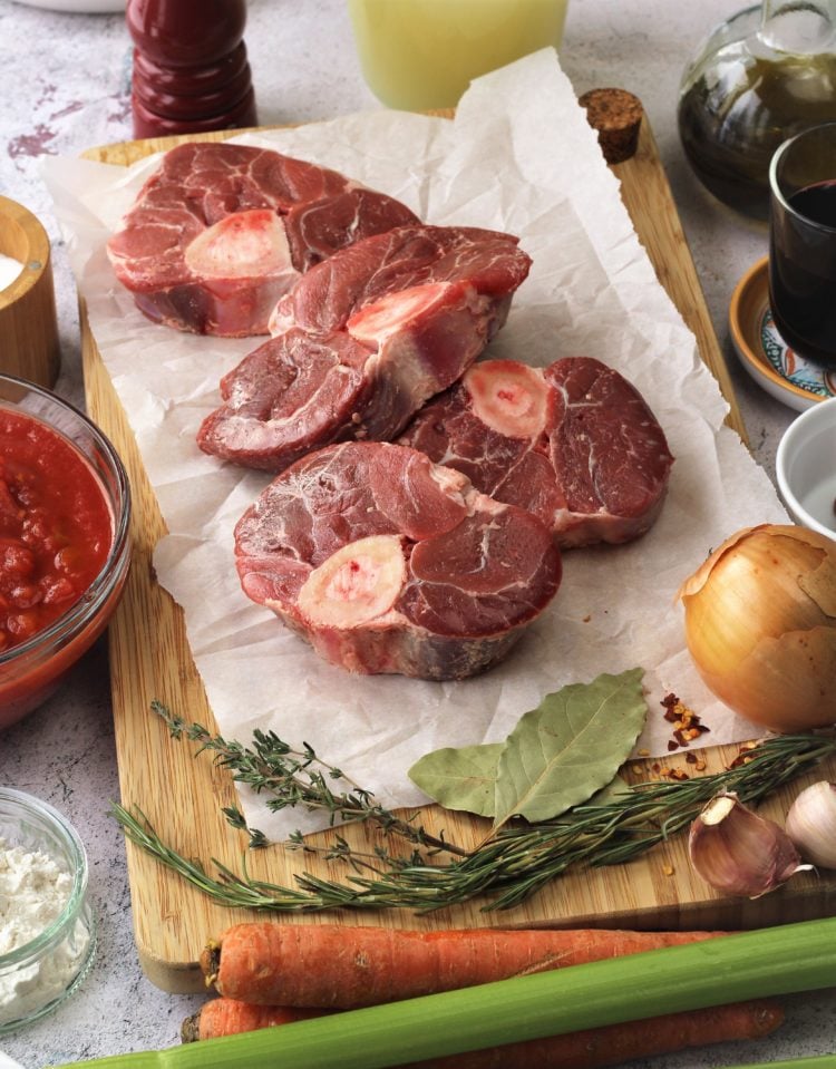 veal shanks on parchment paper along with ingredients for osso buco