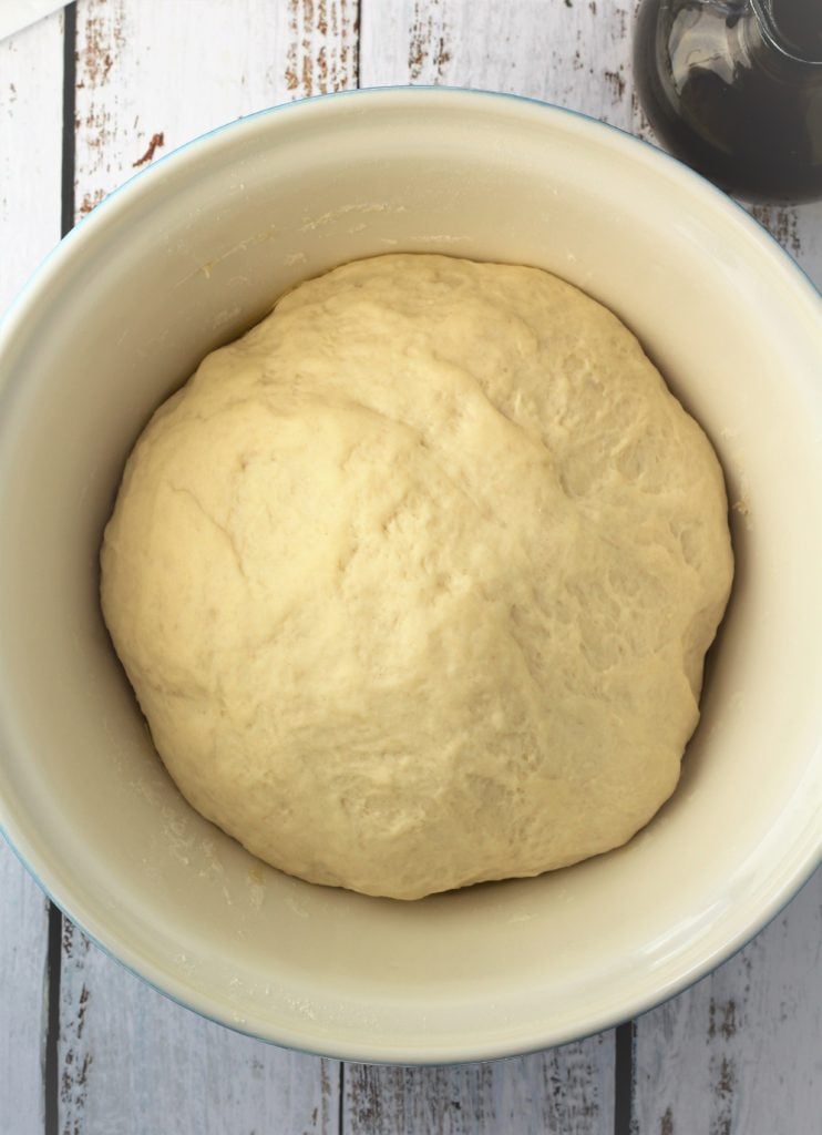 Risen pizza dough in bowl.