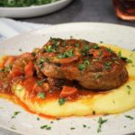 veal osso buco with tomato sauce over polenta topped with gremolata