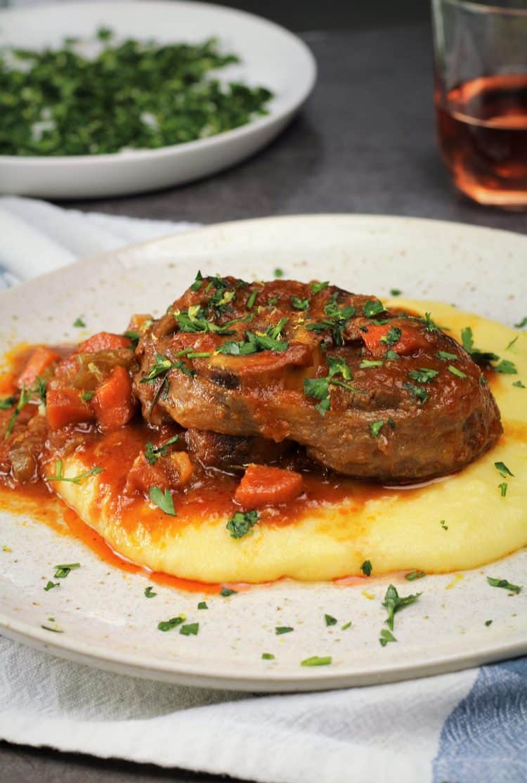 veal osso buco with tomato sauce over polenta topped with gremolata