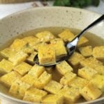 bowl of zuppa imperiale with spoonful of frittata cubes