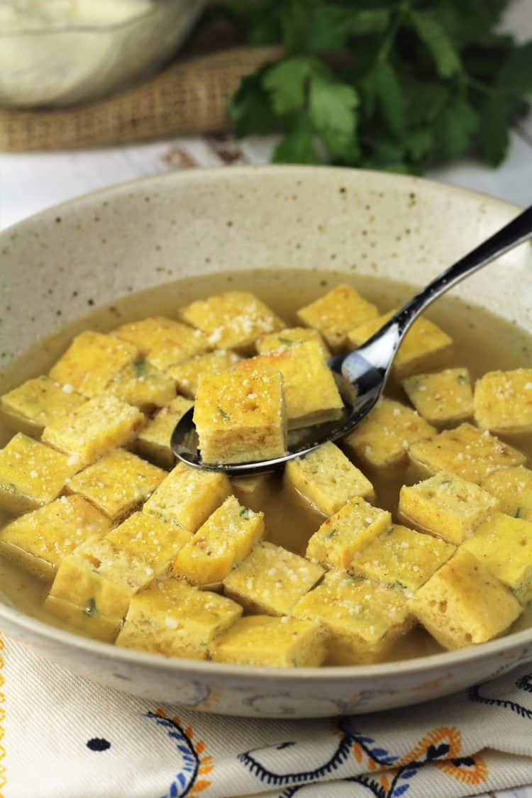 bowl of zuppa imperiale with spoonful of frittata cubes