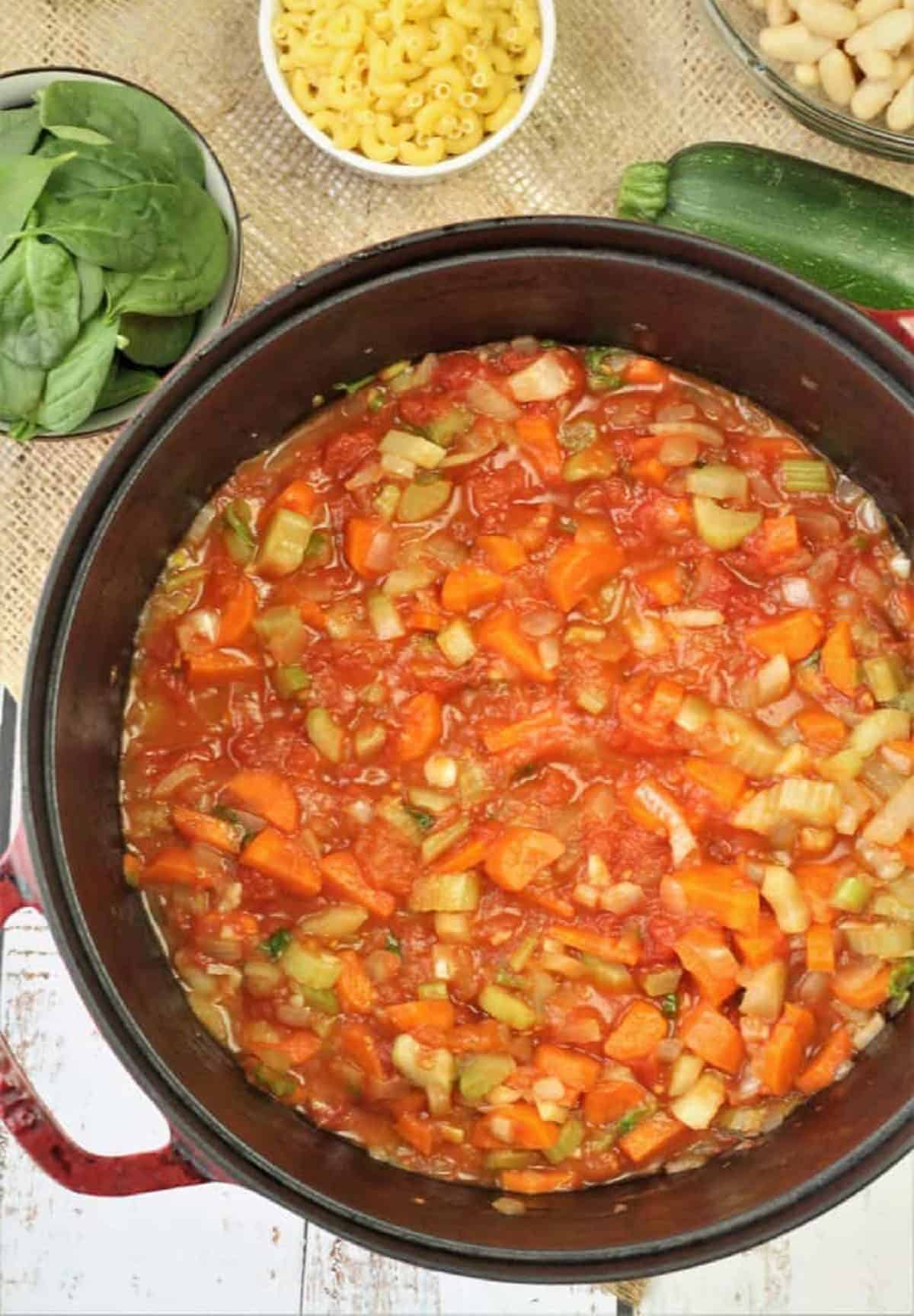 Tomato added to soffrito in sauce pan for minestrone recipe.