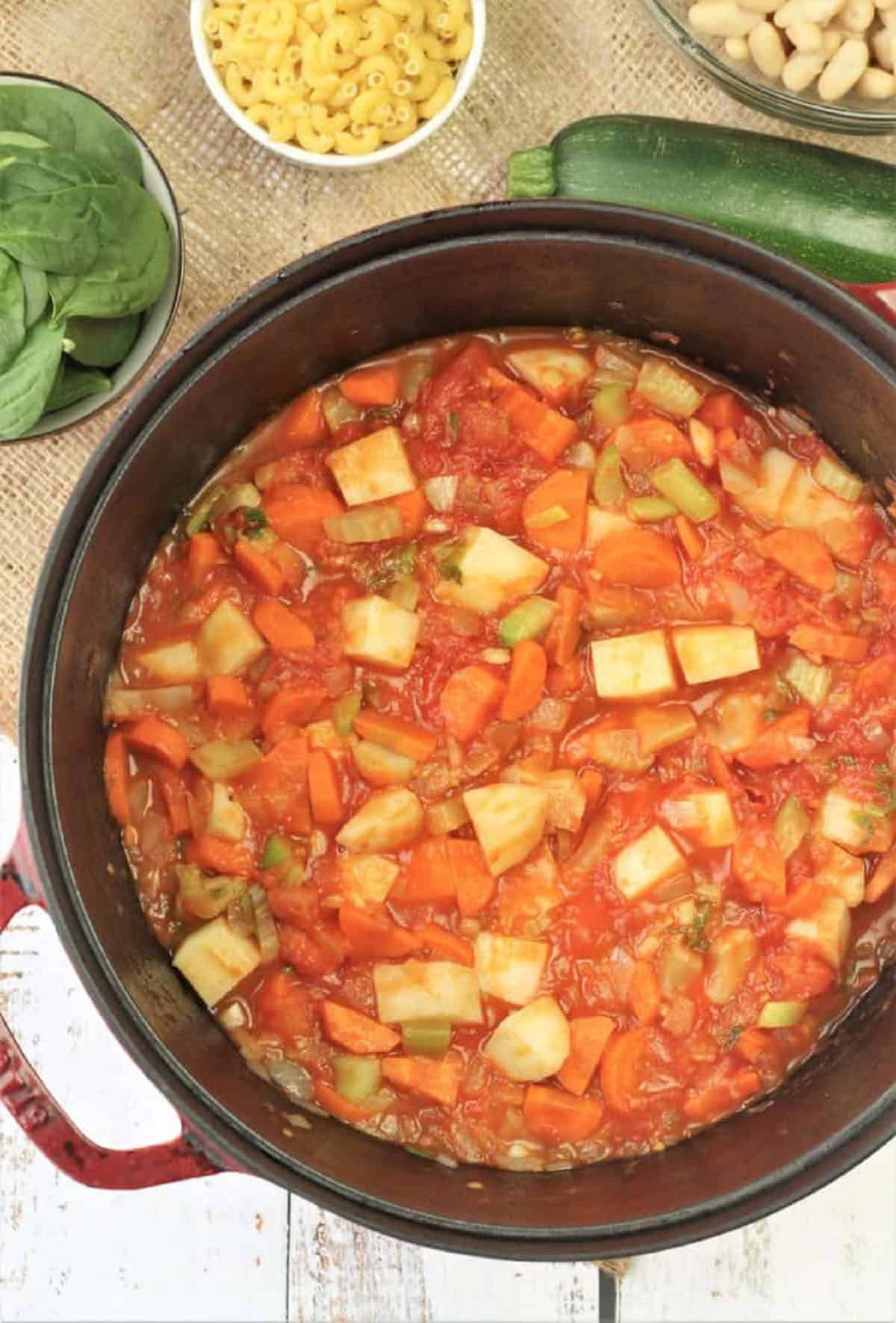 Tomatoes, potatoes, and soffrtito in sauce pan for minestrone recipe.