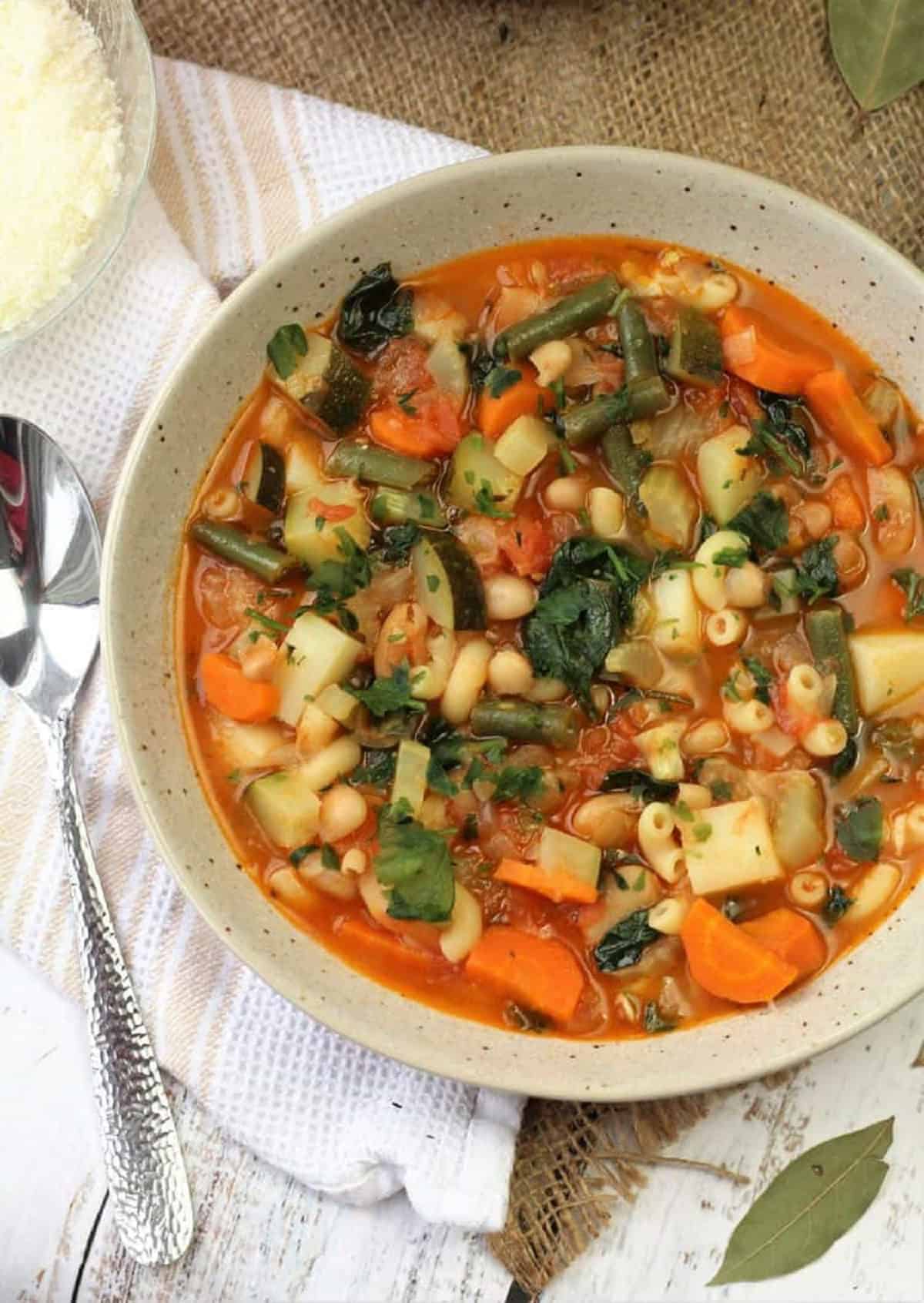Bowl of Italian minestrone soup with spoon on side.
