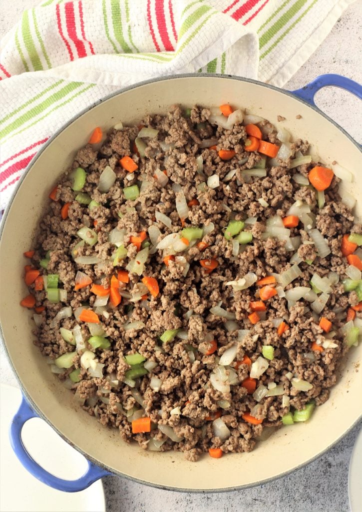 ground beef with onion, carrot and celery in blue skillet