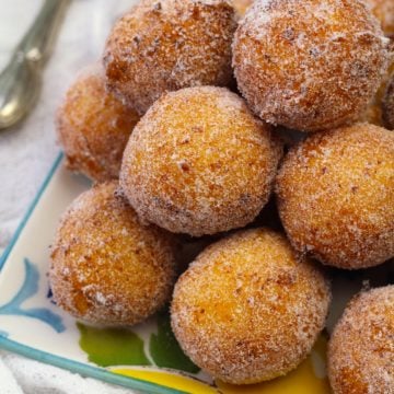 Pile of sugar coated ricotta doughnut holes on plate