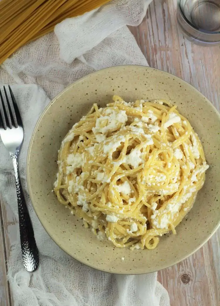 Overhead veiw of bowl filled with spaghetti stirred with ricotta.