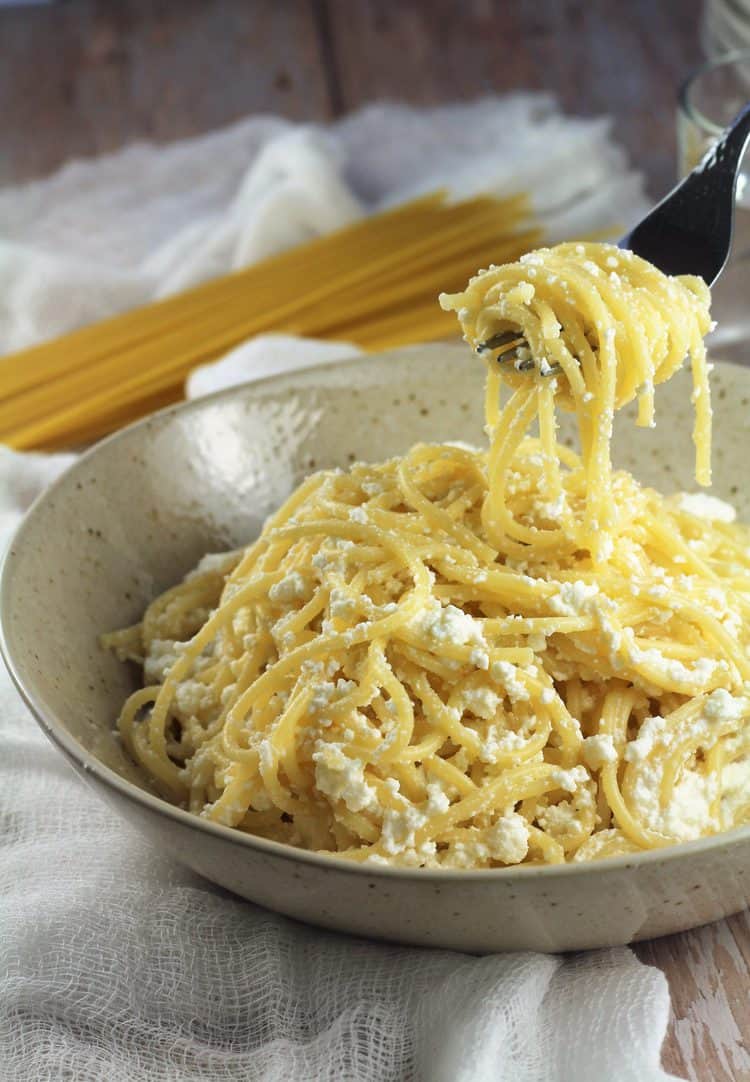 Forkful of spaghtetti with ricotta in bowl.
