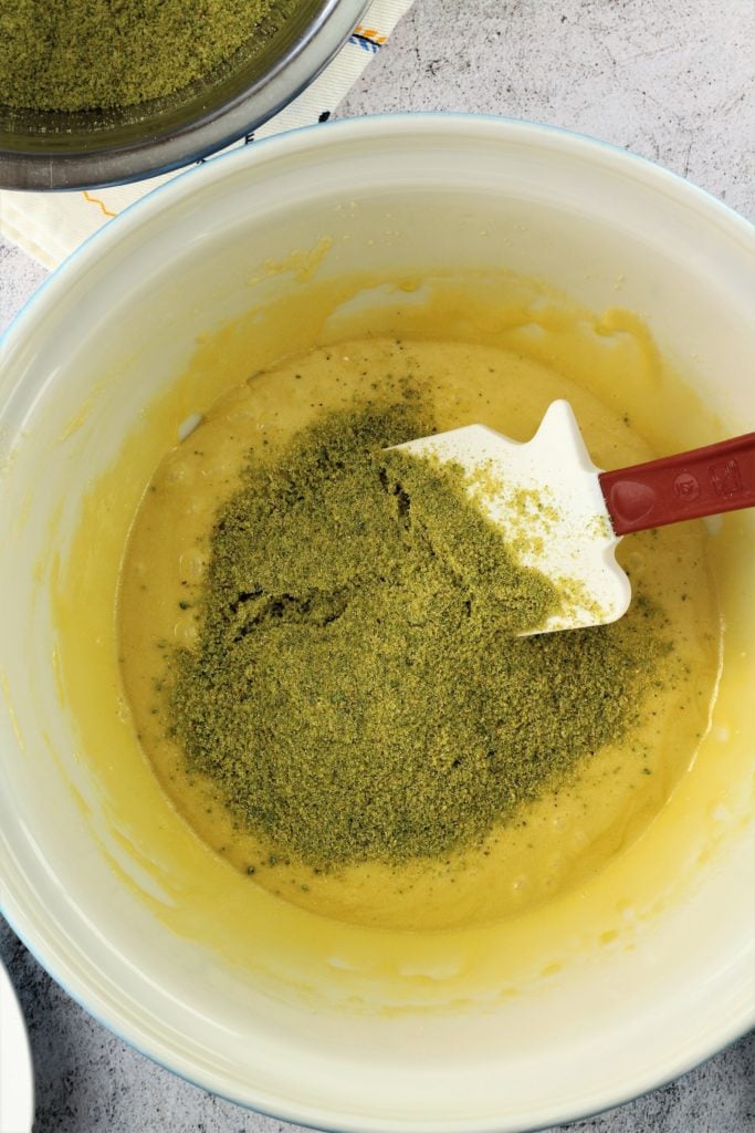 Stirring ingredients for pistachio poleneta cake in bowl.