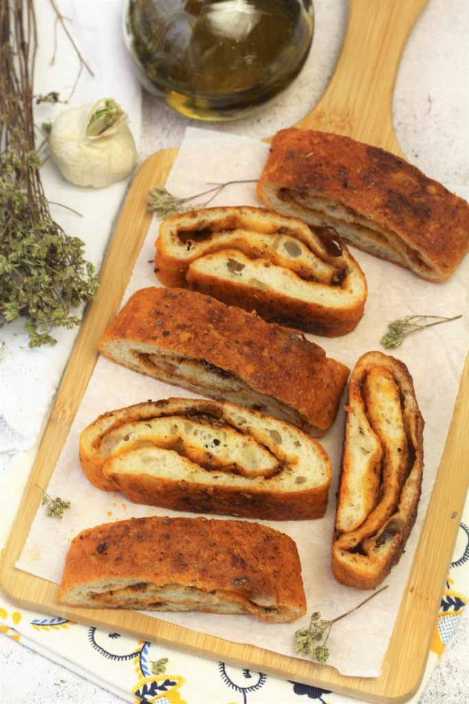 Wedges of garlic herb bread on wood board.