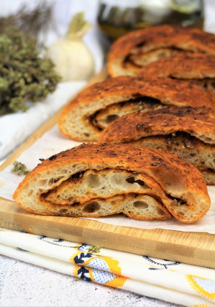 Wedges of paprika garlic herb bread on wood board.