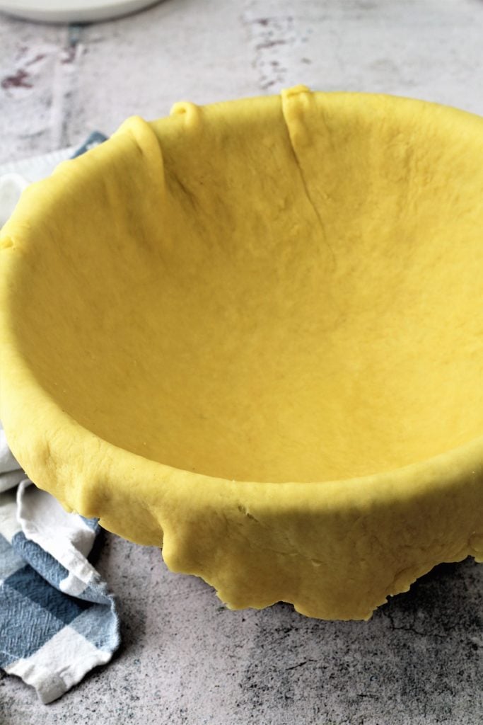 Pastry dough draped over bowl.