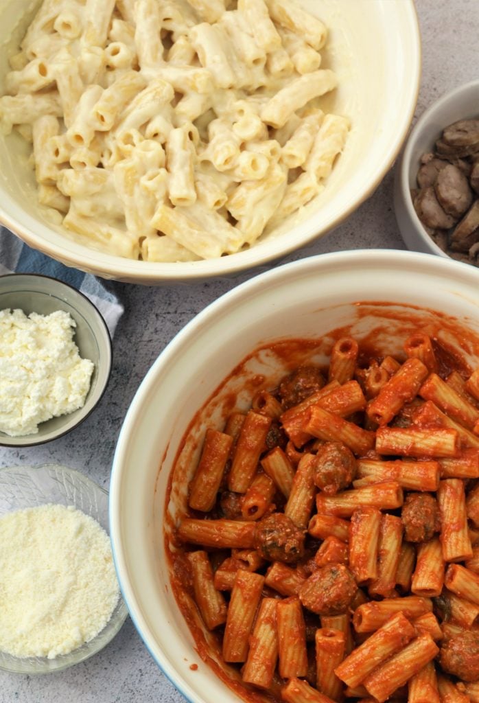 Bowls of pasta tossed with tomato sauce and bechamel sauce for timpano.-b