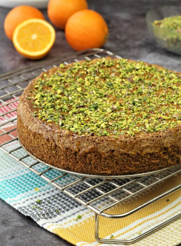 Polenta cake topped with pistachios on wire rack.