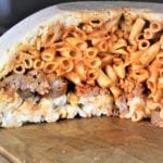 Unmolded timpano pasta dome on wood board.