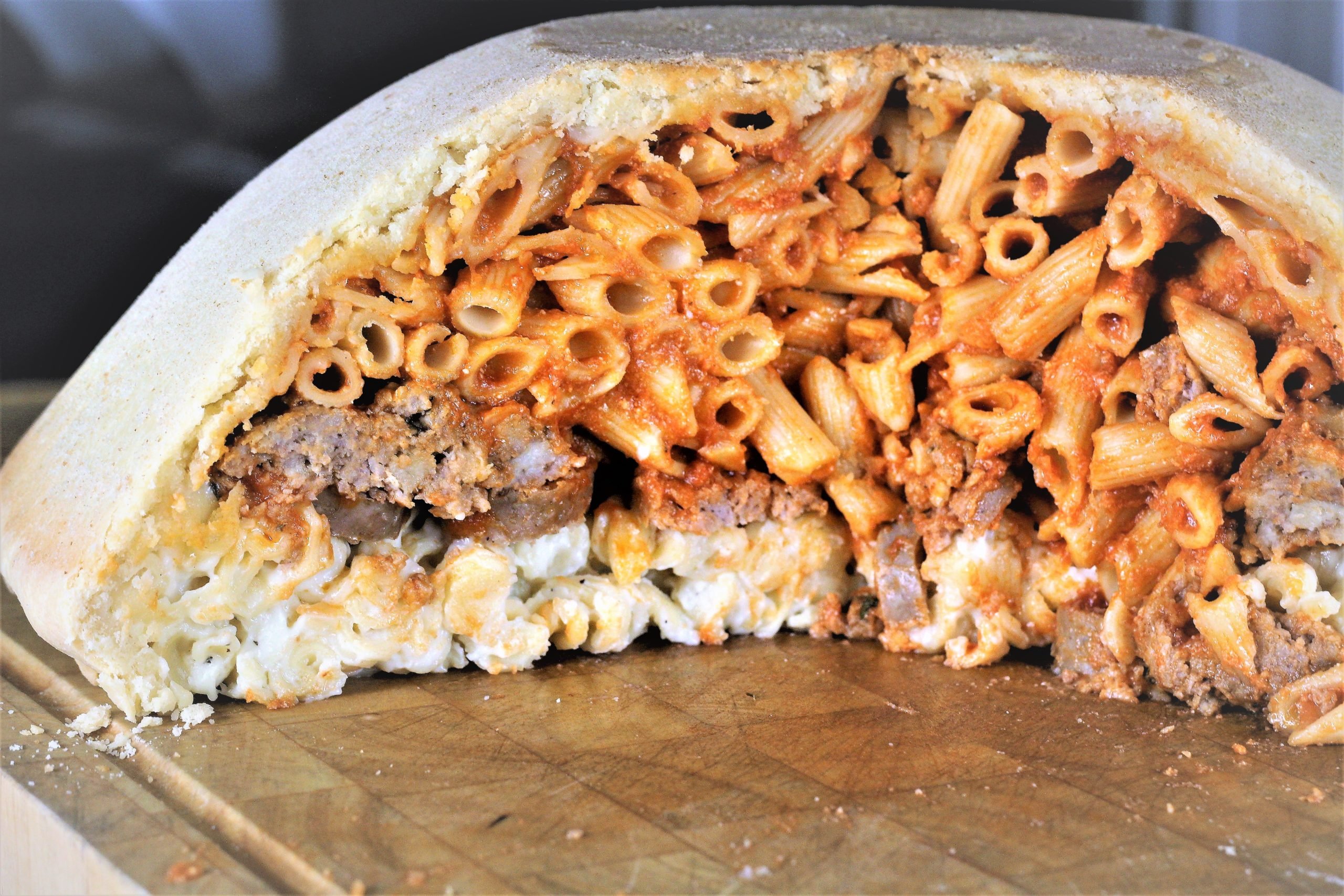 Unmolded timpano pasta dome on wood board.