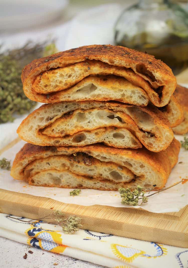 Stacked herb bread wedges on wood board.