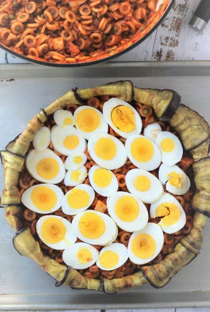 Hard boiled egg slices on pasta in an with eggplant.