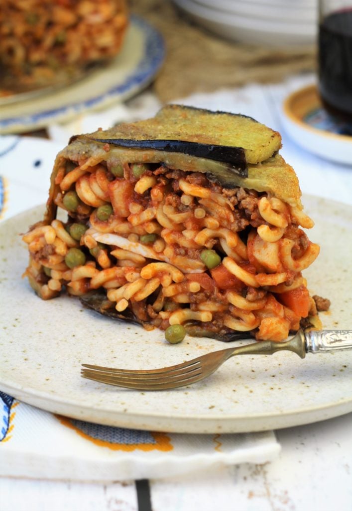 Wedge of pasta baked in eggplant slices on plate.