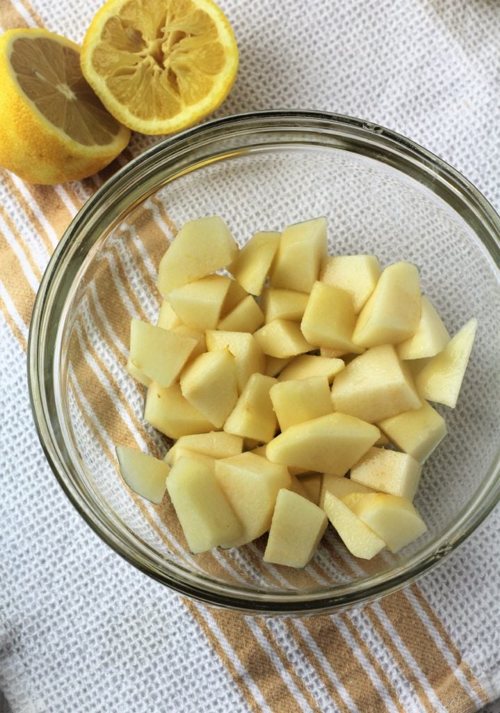 Cubed pear pieces in bowl alongside halved lemon.