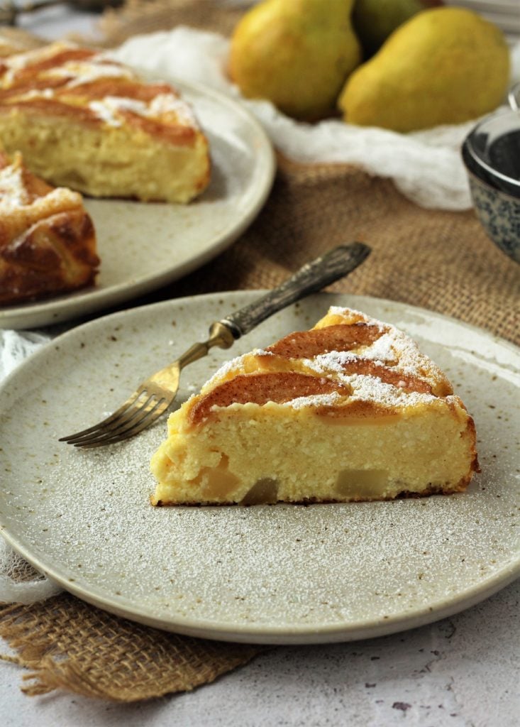 Slice of pear ricotta cheesecake on plate with fork.