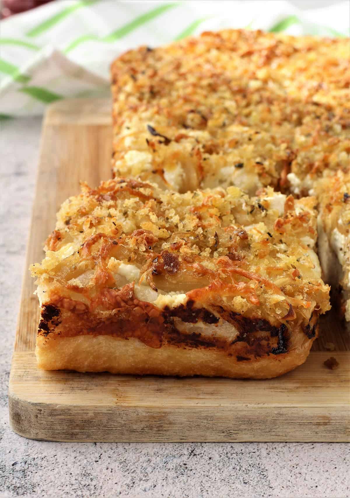 Sfincione Bagherese wedge served on wood board.