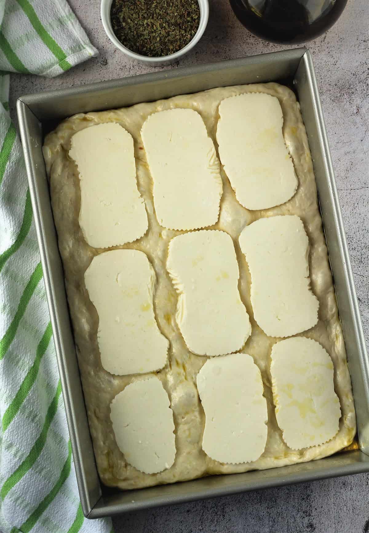 Sfincione dough topped with tuma cheese slices.