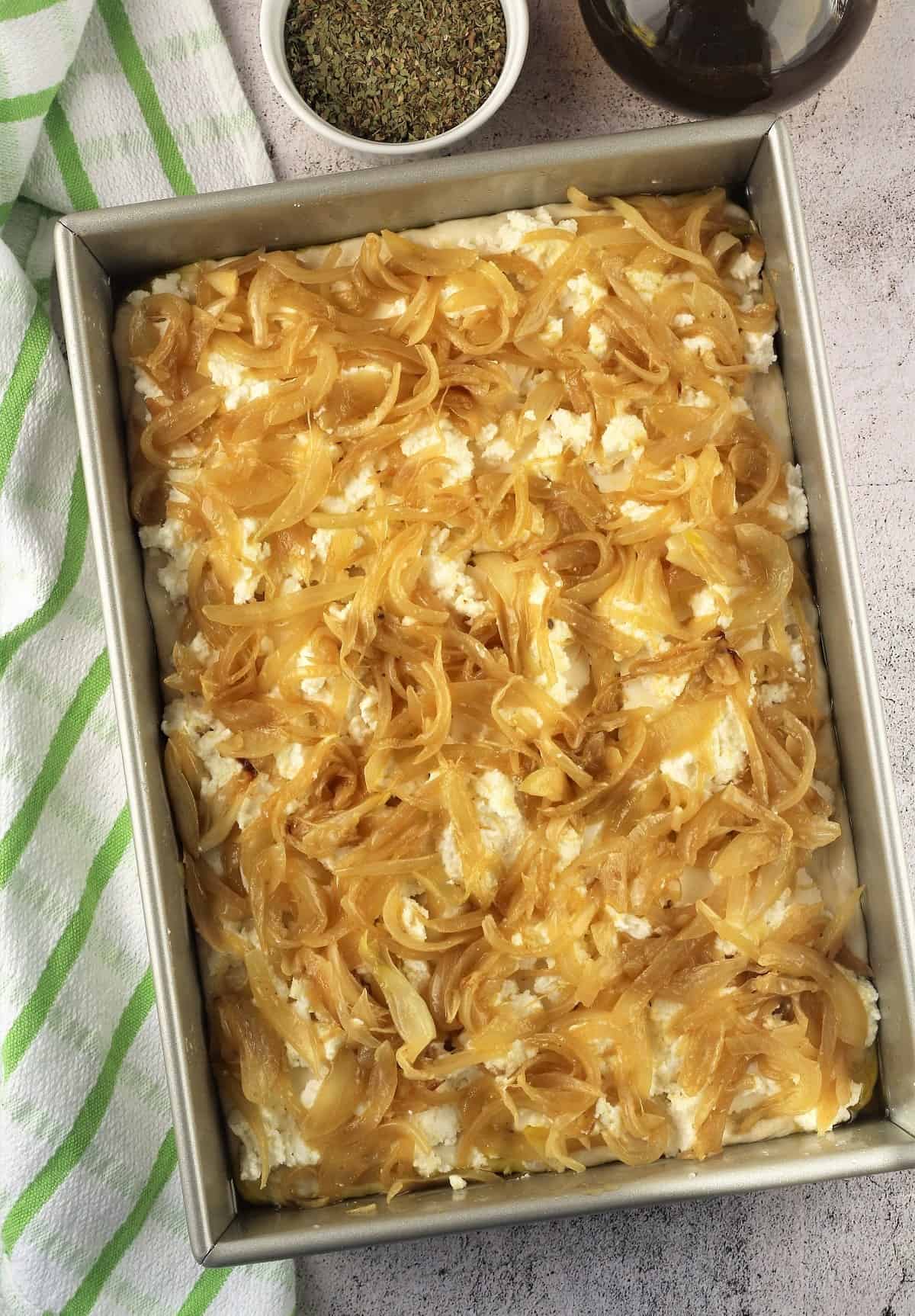 Sfincione dough topped with sautéed onions.