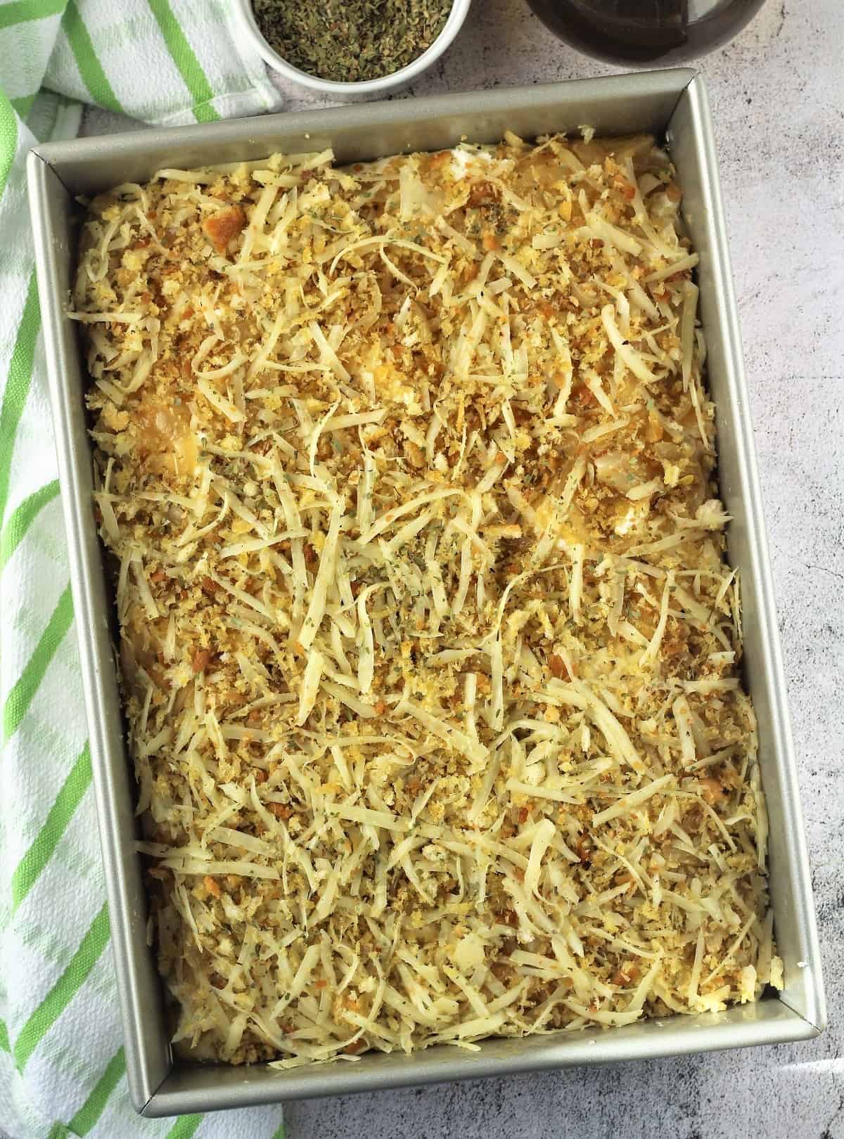 Sfincione Bagherese in pizza pan topped with onion, breadcrumb mixture.