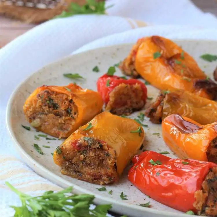 Stuffed mini peppers with bread crumbs on plate with parsley.