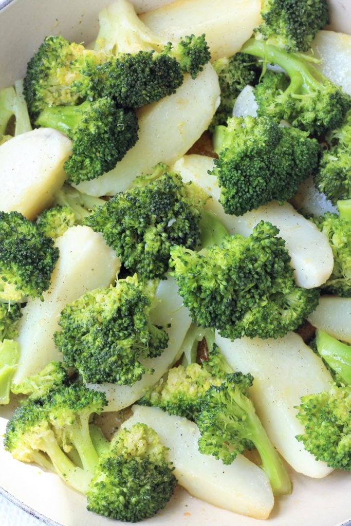 Close up of broccoli florets and potato wedges.