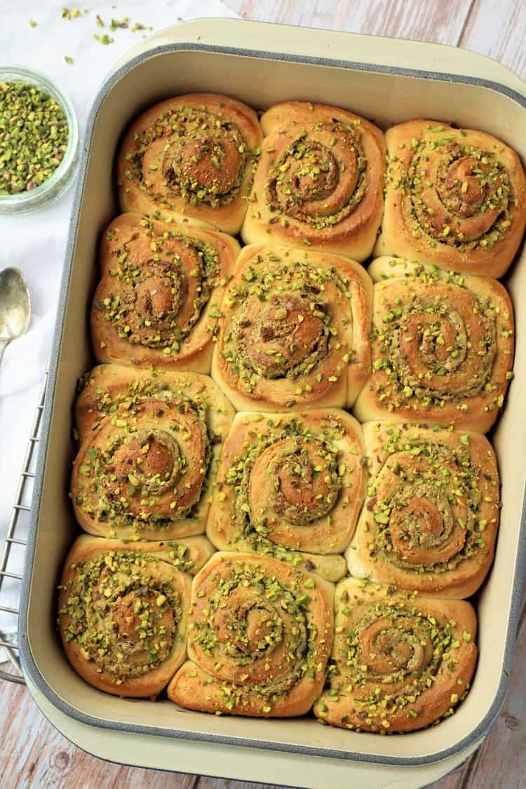 Baking pan with pistachio cream rolls on wire rack.