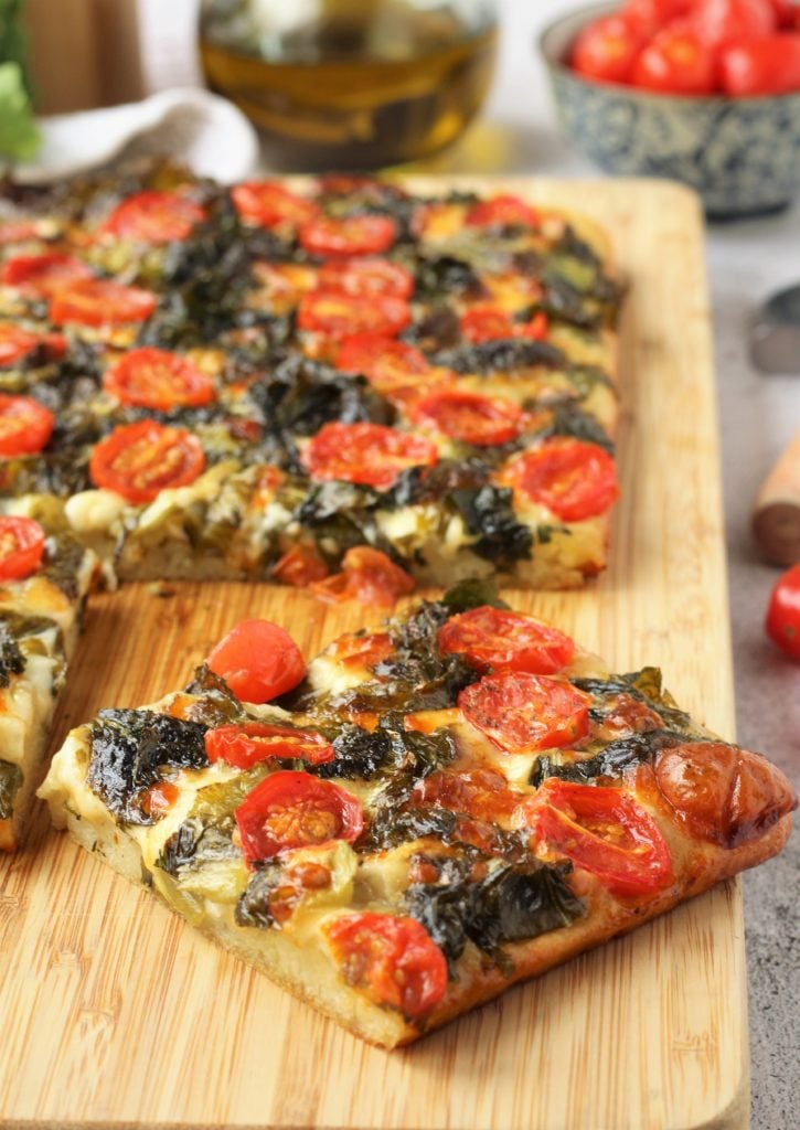 Square of focaccia messinese with escarole and cherry tomatoes.